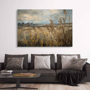 May include: A large rectangular canvas art print depicting a field of tall, dried grasses and wildflowers under a textured, cloudy sky. The color palette is primarily muted yellows, browns, and blues, creating a serene landscape.
