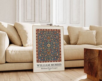 May include: A framed print of the William Morris Holland Park Carpet from 1834. The artwork features a detailed floral pattern in shades of blue, red, and gold. The print is displayed in a gold frame and rests against a beige sofa.