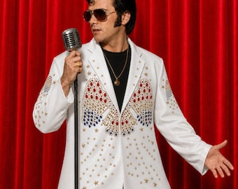 Puede incluir: Un blazer blanco con adornos de estrellas doradas y un patrón central de pedrería roja, blanca y azul. El blazer se lleva sobre una camisa negra con un collar de cadena dorada, combinado con gafas de sol oscuras y un soporte de micrófono plateado.