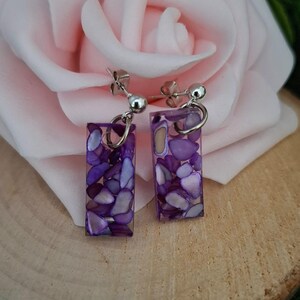 May include: Purple and white rectangular earrings with a silver post and back. The earrings are made of resin and have a speckled appearance.