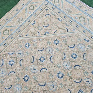Puede incluir: Alfombra beige y azul estampada. La alfombra presenta un dise&ntilde;o geom&eacute;trico repetitivo con detalles en azul, azul claro y verde. La alfombra tiene un borde detallado y una paleta de colores suaves y neutros.
