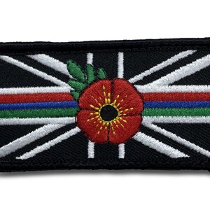 Op de afbeelding: Zwarte geborduurde patch met een wit Union Jack-ontwerp, een rode klaproos met een gele kern en een dunne blauw-rood-groene streep.