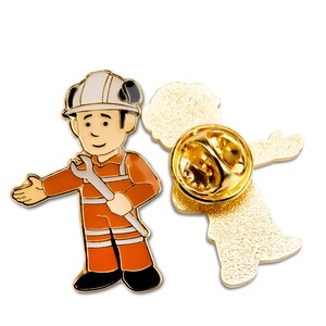 Peut inclure: Épinglette en métal doré représentant un dessin animé d'un ouvrier portant un casque et tenant une clé à molette. L'épingle est fixée à un dos d'épingle standard.