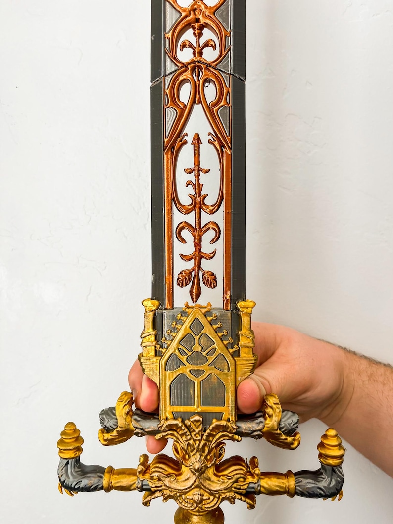 May include: A gold and black decorative sword with intricate details. The sword has a gold handle with a black and gold design. The blade is black with gold accents.