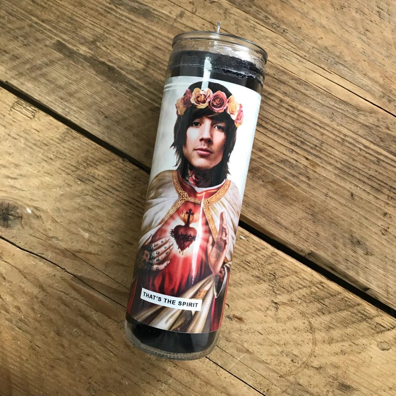 Pode incluir: Uma vela preta e branca com uma imagem de um homem com uma coroa de flores e um cora&ccedil;&atilde;o no peito. O texto "THAT'S THE SPIRIT" est&aacute; impresso na vela.