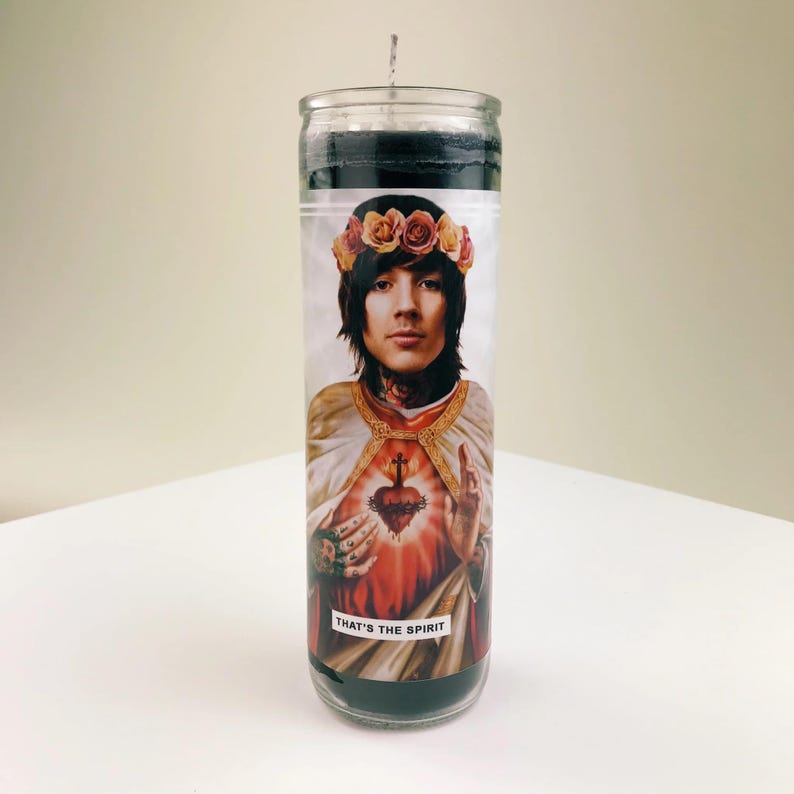 Pode incluir: Uma vela preta com uma imagem impressa de um homem com uma coroa de flores, um cora&ccedil;&atilde;o vermelho e o texto "THAT'S THE SPIRIT".