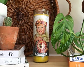 Puede incluir: Una vela amarilla con una imagen de una mujer con una corona de flores en la cabeza. El texto en la vela dice "Puede que esté equivocada, pero francamente lo dudo."