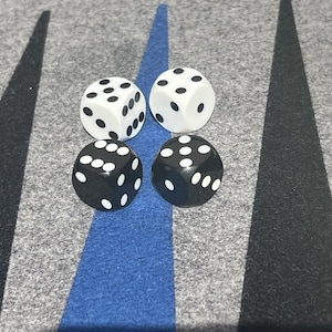 May include: Four dice, two black and two white, on a gray and blue surface. The dice are arranged in a square pattern.