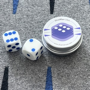 Könnte beinhalten: Zwei weiße Würfel mit blauen Punkten und eine silberne Dose mit einem lila und weißen Logo, auf dem "DiceMan USA" und "www.dicemanusa.com" steht.