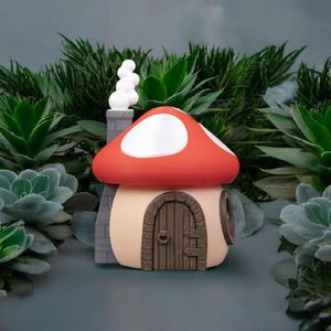 May include: A small, red and white mushroom-shaped house with a brown door and a gray chimney. The house is surrounded by green plants.