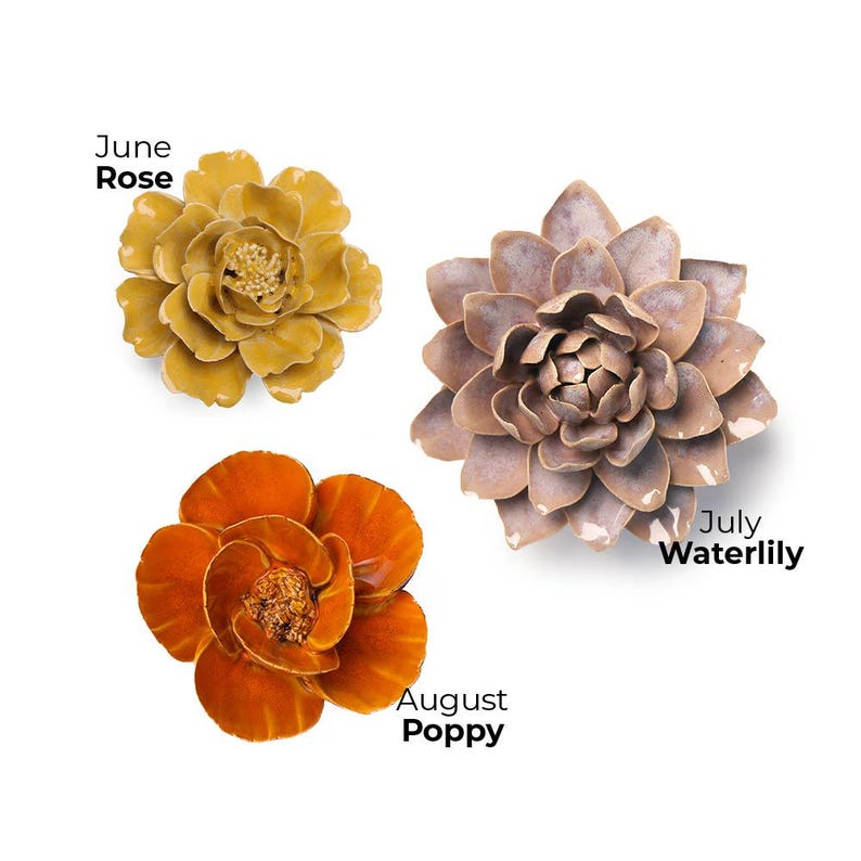 Pode incluir: Tr&ecirc;s esculturas de flores de cer&acirc;mica: uma Rosa de junho amarela, um Nen&uacute;far de julho malva e uma Papoila de agosto laranja. Cada flor tem p&eacute;talas detalhadas e um centro texturizado. As flores s&atilde;o exibidas em um fundo branco.