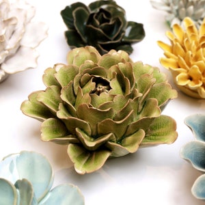 May include: A collection of ceramic flowers in various colors and styles. The flowers are arranged in a circular pattern on a white background. The flowers are all different sizes and shapes, and they have a variety of textures. The flowers are all made of ceramic and have a glazed finish.