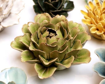 May include: A collection of ceramic flowers in various colors and styles. The flowers are arranged in a circular pattern on a white background. The flowers are all different sizes and shapes, and they have a variety of textures. The flowers are all made of ceramic and have a glazed finish.