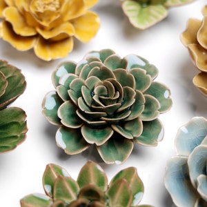 May include: A collection of ceramic flower wall decor in various colors and styles. The flowers are made of glazed ceramic and have a realistic appearance.