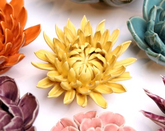 May include: A collection of ceramic flower wall decor in various colors, including yellow, orange, pink, purple, and blue. The flowers are all in a realistic style and have a 3D effect.