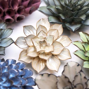 May include: A collection of ceramic succulent flower wall decor in various colors, including white, blue, green, and purple. The flowers are made of glazed ceramic and have a realistic appearance.