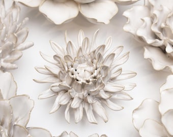 May include: A set of white ceramic flowers with a textured finish. The flowers are arranged in a circular pattern on a white background.