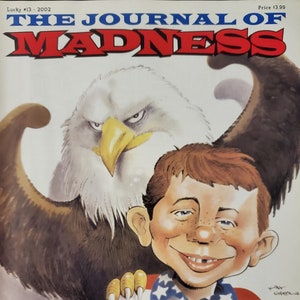 Puede incluir: La portada de la revista The Journal of Madness con un personaje de dibujos animados que lleva una camisa roja, blanca y azul con estrellas y un águila calva. El texto "The Dave Berg Interview" está en la parte inferior de la portada.