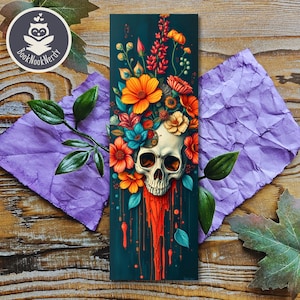 Peut inclure: Un marque-page rectangulaire pr&eacute;sentant un cr&acirc;ne humain central orn&eacute; d'un arrangement vibrant de fleurs orange, rouges, jaunes et bleu sarcelle. Sous le cr&acirc;ne, un liquide orange vif coule vers le bas sur un fond bleu sarcelle fonc&eacute;.