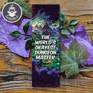 Könnte beinhalten: Ein farbenfrohes Lesezeichen mit einer Berglandschaft und dem Text "The World's Okayest Dungeon Master".