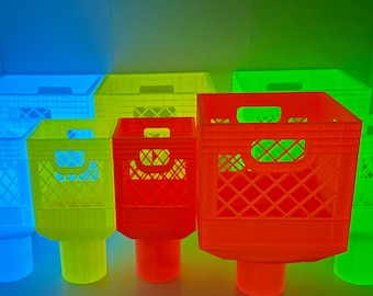 May include: A collection of colorful, neon-hued milk crate-style containers. The crates are in shades of blue, yellow, green, and red, each mounted on a cylindrical base. The crates have a diamond-patterned design.