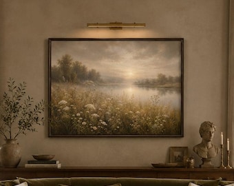 May include: A curved olive green sofa with beige throw pillows, positioned in front of a landscape painting. A square travertine coffee table sits in the center, holding a glass vase with white flowers and ceramic bowls, flanked by two armchairs.