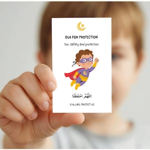 May include: A white card held by a person features the text "DUA FOR PROTECTION" and "For: Safety and protection." A cartoon superhero with a red cape and purple mask is also on the card. The bottom of the card has Arabic text and the English translation "O ALLAH, PROTECT US."