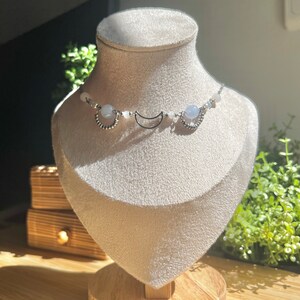 Op de afbeelding: Een zilveren choker ketting met blauwe en witte kralen en halve maan bedels.