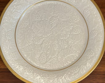 Könnte beinhalten: Ein weißer Keramik-Dinnerteller mit goldfarbenem Rand und einem geprägten Weinreben-Design.
