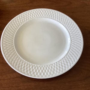 Könnte beinhalten: Weiße Keramik-Dinnerplatte mit einem gewebten Muster am Rand.
