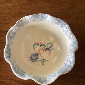 May include: A white ceramic bowl with a blue and white scalloped rim and a hand-painted floral design in pink, green, and blue.