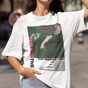 May include: White t-shirt with a black and white image of a woman with the text "The Smiths" and "The Queen Is Dead" printed on the front. The text includes song titles from the album, "The Queen Is Dead".
