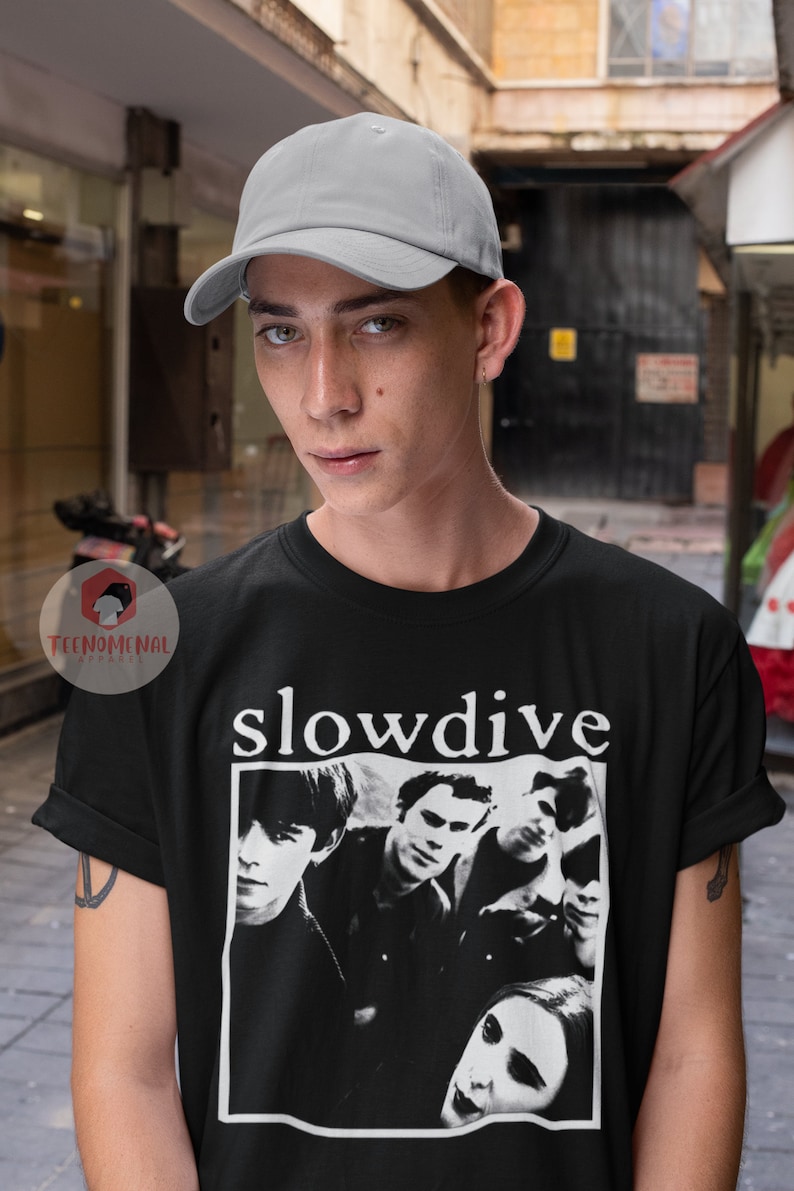 May include: A black t-shirt with a white print of a band called "slowdive". The band members are pictured in black and white. The person wearing the shirt is also wearing a gray baseball cap.
