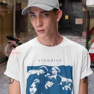 Puede incluir: Una camiseta blanca con un gr&aacute;fico azul y blanco de la banda Slowdive. El gr&aacute;fico incluye el nombre de la banda y el t&iacute;tulo del &aacute;lbum "souvlaki (1993)".
