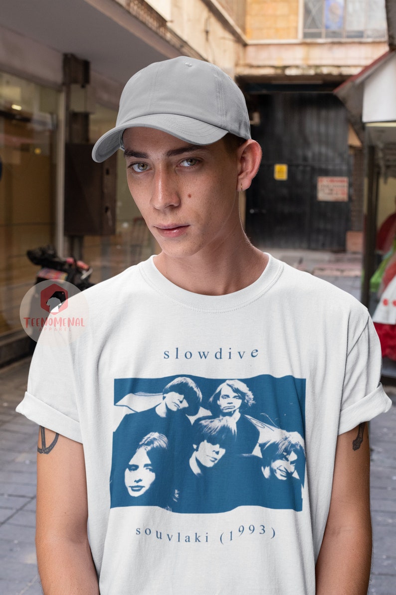 Puede incluir: Una camiseta blanca con un gr&aacute;fico azul y blanco de la banda Slowdive. El gr&aacute;fico incluye el nombre de la banda y el t&iacute;tulo del &aacute;lbum "souvlaki (1993)".