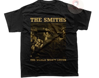 Puede incluir: Camiseta negra con una imagen de estilo vintage de los miembros de la banda The Smiths. El texto "THE SMITHS" y "THE WORLD WON'T LISTEN" está impreso en dorado en la camiseta.