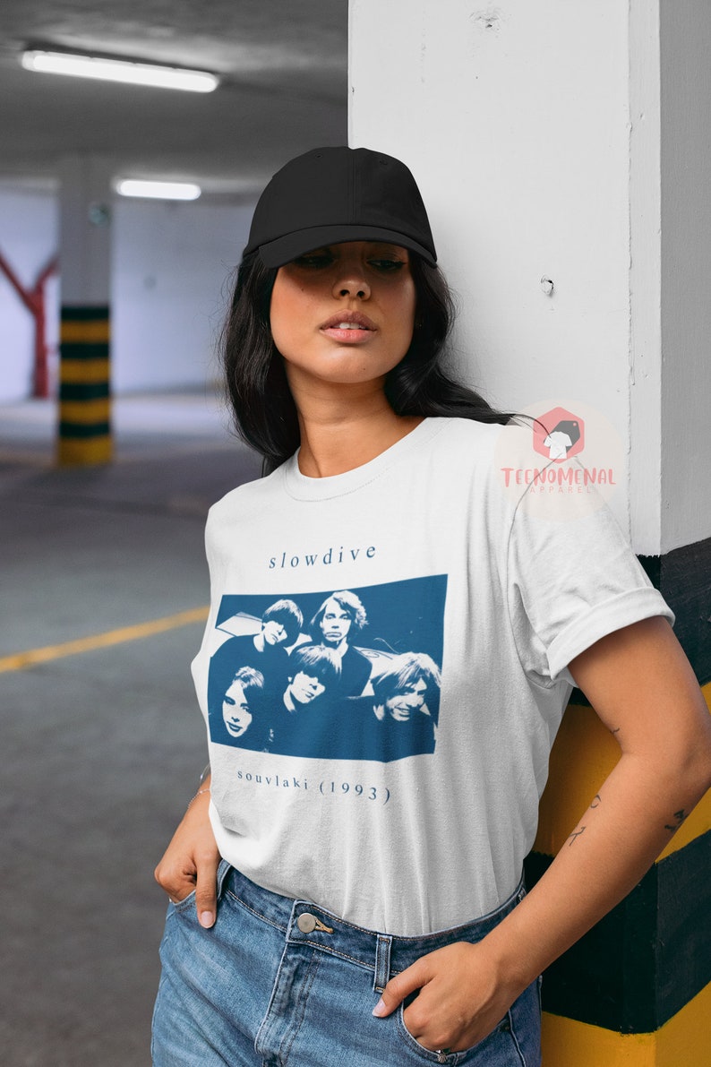 Puede incluir: Camiseta blanca con un gr&aacute;fico azul de la banda Slowdive y el t&iacute;tulo del &aacute;lbum "souvlaki (1993)".