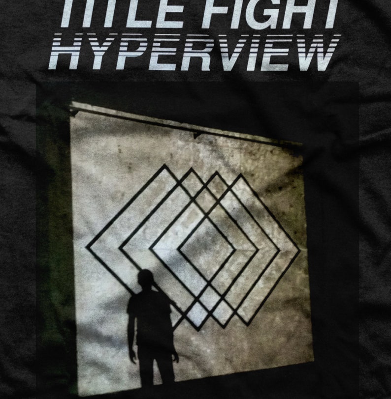 May include: A black and white image of a person standing in front of a wall with a geometric pattern of overlapping squares. The text "TITLE FIGHT HYPERVIEW" is at the top of the image.