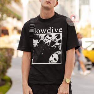 May include: A black t-shirt with a white graphic of the band "Slowdive" on the front. The band members are pictured in black and white. The shirt has a crew neck and short sleeves.