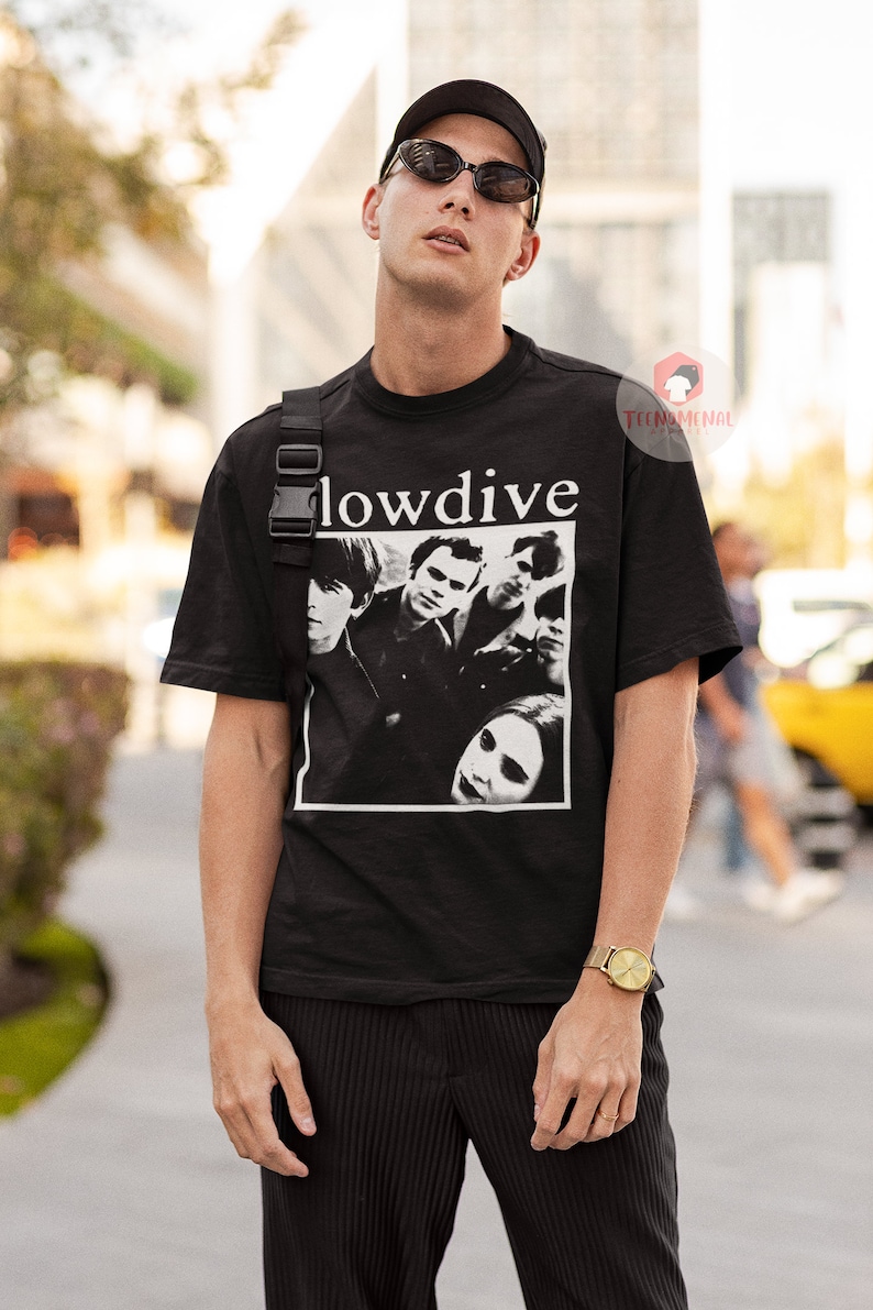 May include: A black t-shirt with a white graphic of the band "Slowdive" on the front. The band members are pictured in black and white. The shirt has a crew neck and short sleeves.