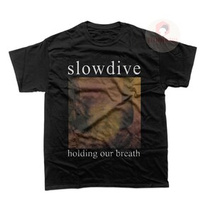 May include: Black t-shirt with the band name "slowdive" printed in white text and the album title "holding our breath" printed below a blurry image of a person's face.