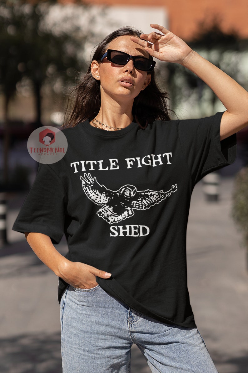 Puede incluir: Camiseta negra con un gr&aacute;fico blanco de un b&uacute;ho en vuelo y el texto "TITLE FIGHT SHED".