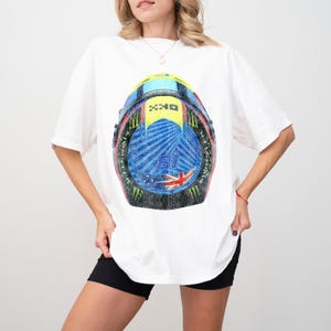 May include: White t-shirt with a blue, red, yellow, and black graphic of a motorcycle helmet. The helmet has a checkered flag design and the number 89 on the side.