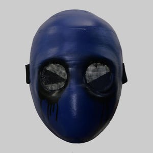 May include: A blue mask with mesh eye coverings and black tear-like streaks. The mask has a smooth, rounded shape and black straps on the sides. The eye coverings are triangular in shape.