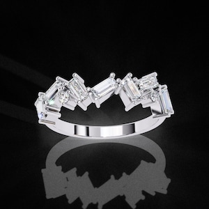 May include: A silver-toned ring featuring a series of clear, rectangular baguette-cut stones and small round-cut stones arranged in an irregular, staggered pattern along the top half of the band, creating a jagged, multi-level profile.