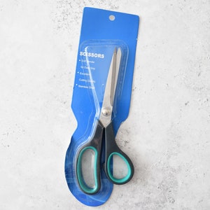 Peut inclure: Une paire de ciseaux noirs et verts avec une lame en acier inoxydable, emballés dans une pochette en plastique bleue. L'emballage indique des caractéristiques telles que poignée souple, prise en main facile, excellente qualité de coupe et acier inoxydable.