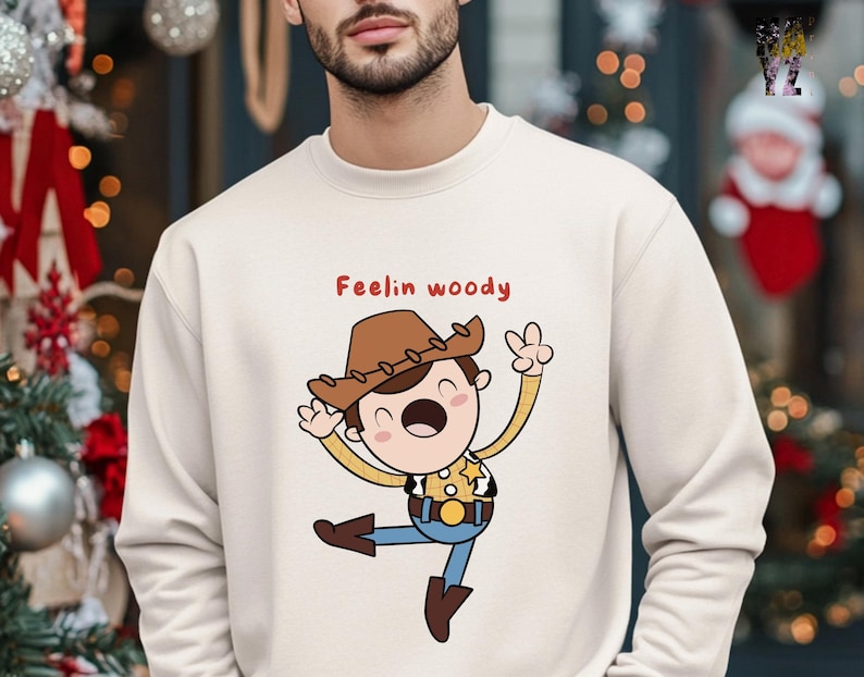 Puede incluir: Una sudadera de color crema con una ilustraci&oacute;n de dibujos animados de Woody de Toy Story. El texto "Feelin' Woody" est&aacute; impreso en rojo sobre la ilustraci&oacute;n.