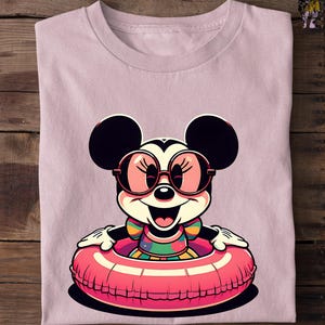 May include: A light pink t-shirt featuring a cartoon image of Minnie Mouse wearing sunglasses and a colorful swimsuit, floating in a pink inner tube. The design has a retro, cartoon style.