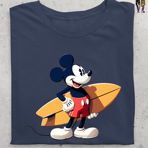Op de afbeelding: Marineblauw T-shirt met een cartoon van Mickey Mouse met een gele surfplank. Mickey draagt een rode korte broek, witte handschoenen en schoenen. Het T-shirt heeft een ronde hals.