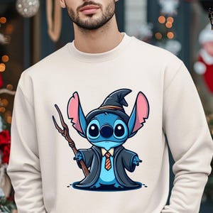 K&ouml;nnte beinhalten: Ein wei&szlig;es Sweatshirt mit einer blauen Comicfigur, die einen schwarzen Zaubererhut und eine Robe tr&auml;gt. Die Figur h&auml;lt einen Zauberstab und hat eine rot-gelbe Krawatte.